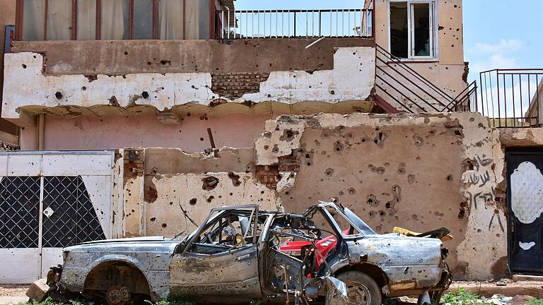 Konflikt im Sudan       -  Ein zerstörtes Auto steht im sudanesischen Omdurman vor einem Haus voller Einschüsse. (Archivbild)
