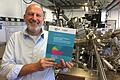 Prof. Ralph Claessen, Inhaber des Lehrstuhls für Experimentelle Physik IV an der Uni Würzburg vor einer Ultra-Hoch-Vakuum-Anlage. Claessen ist Sprecher des Exzellenzclusters zu Quantenmaterialien - im Verbund mit der TU Dresden. In der Hand hält er den erfolgreichen, 195 Seiten starken Antrag.