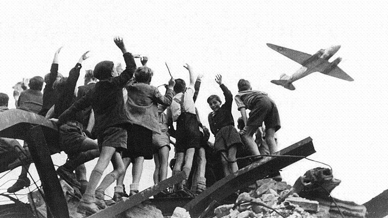 70 Jahre Luftbrücke       -  Das Foto aus dem Jahr 1948 zeigt West-Berliner Jungen, die einem US-amerikanischen Transportflugzeug winken.