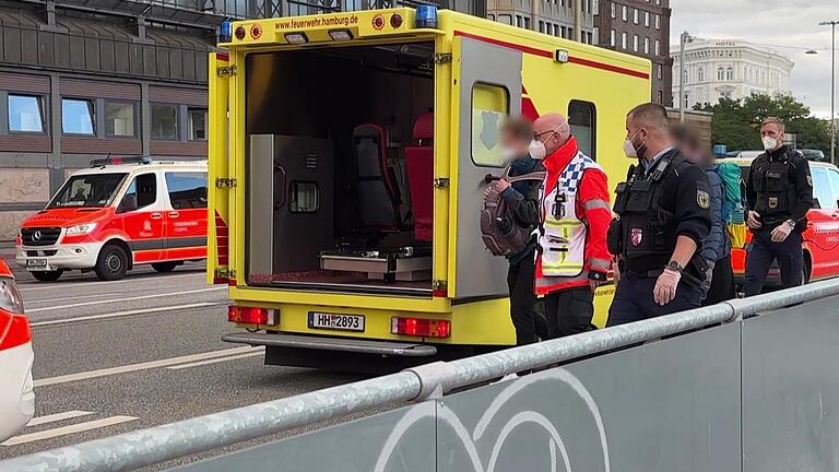 Verdacht auf Infektion: Bahnsteig in Hamburg gesperrt - Einsatzkräfte mit Mundschutz begleiten zwei Menschen zum Rettungswagen der Feuerwehr vor dem Hauptbahnhof. Verdacht auf Infektion: Bahnsteig in Hamburg gesperrt - Einsatzkräfte mit Mundschutz begleiten zwei Menschen zum Rettungswagen der Feuerwehr vor dem Hauptbahnhof.