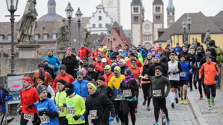 Zahlreiche Menschen laufen im Rahmen des Gedächtnislaufs über die Alte Mainbrücke in Würzburg. Mit dem Lauf erinnern die Veranstalter an die Zerstörung Würzburgs am 16. März 1945.