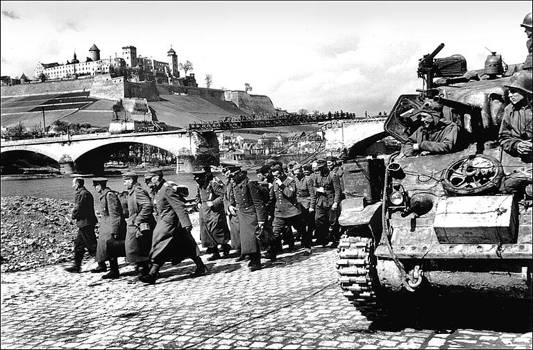 Eine Kolonne deutscher Kriegsgefangener marschiert in die Gefangenschaft.