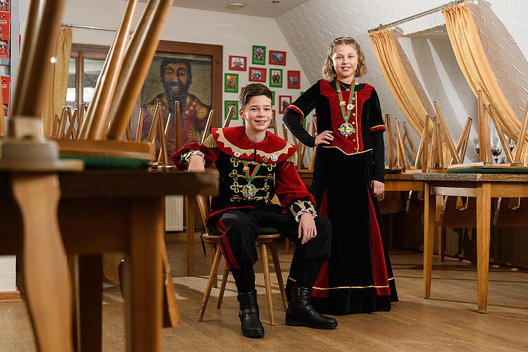 Max Hein und Marie Ehrenfels, 12 und 11, Kinderprinzenpaar der Gilde Giemaul. Es ist still im Vereinsgebäude der Gilde Giemaul im Würzburger Stadtteil Heidingsfeld. Die Stühle im Gastraum sind hochgestellt. „Fasching ist für mich die fünfte Jahreszeit“, sagt Max. Für den Zwölfjährigen fühlt es sich gerade so an, als würde der Sommer ausfallen. Max und Marie sind seit 2020 das Kinderprinzenpaar der Gilde. „Ich vermisse die Abendsitzungen“, sagt Marie. „Wir sind immer hinter der Bühne und machen Blödsinn!“, fügt sie hinzu und lacht. Außerdem tanzt sie gerne. Max fehlen die großen Umzüge. „Und anderen Menschen eine Freude zu machen“, sagt er. Zum Beispiel beim närrischen Besuch im Altenheim. Beide freuen sich auf das Sommerfest der Gilde.