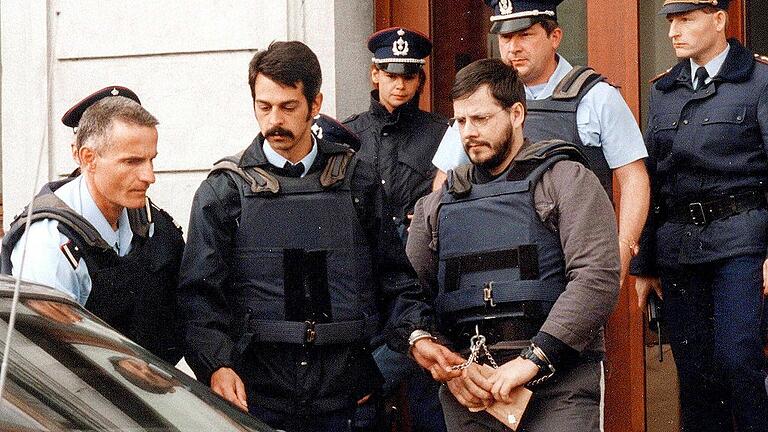 Der Fall Dutroux       -  Marc Dutroux (in Handschellen) wird im Jahr 2000 von Polizeibeamten nach einer Anhörung aus dem Justizpalast geführt. Sechs Mädchen und junge Frauen hatte Dutroux in den 90er Jahren entführt, in einem Kellerverlies gefoltert und vergewaltigt &ndash; vier von ihnen starben.