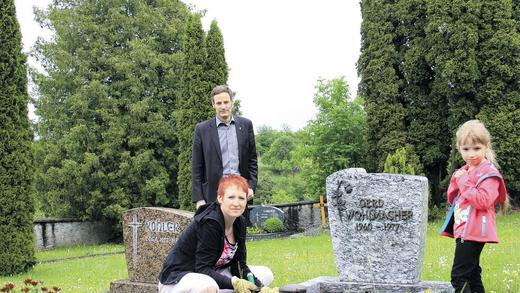 Zeit für Neugestaltung: Auf der Wiese hinter dem Grab, das Daniela Wohlmacher mit ihrer Tochter Johanna bepflanzt, wird im Burgpreppacher Friedhof ein Grabfeld für Urnen entstehen. Mit im Bild ist Pfarrer Peter Bauer zu sehen. Die evangelische Kirchengemeinde plant die Urnengräber.