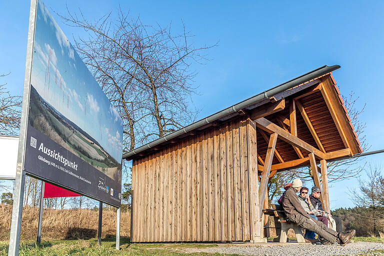 Menschen unterhalten sich an dem Aussichtspunkt am Glösberg. Hier kann man überdacht rasten und einen schönen Ausblick ins Kitzinger Land genießen. Menschen unterhalten sich an dem Aussichtspunkt am Glösberg. Hier kann man überdacht rasten und einen schönen Ausblick ins Kitzinger Land genießen.