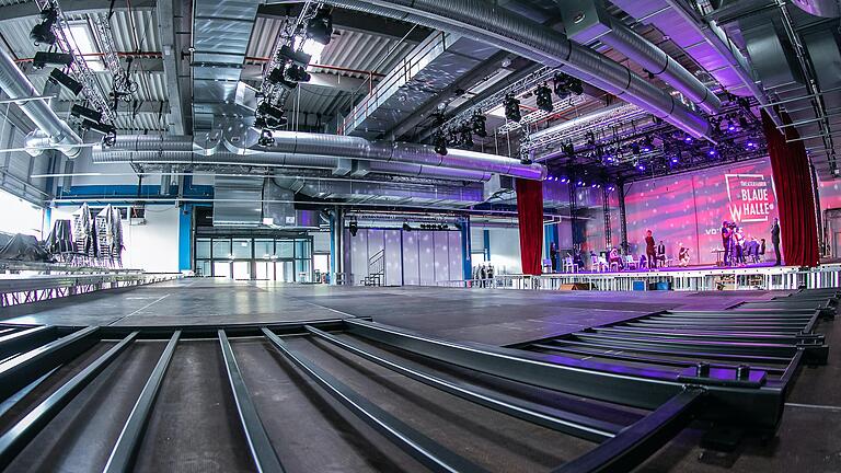 Noch herrscht hier Baustelle: Die Blaue Halle der va-Q-tec AG in der Dürrbachau wird künftig Spielort großer Produktionen des Mainfranken Theaters sein. Rechts sieht man die Bühne, im Vordergrund wird gerade die Zuschauertribüne aufgebaut. Noch herrscht hier Baustelle: Die Blaue Halle der va-Q-tec AG in der Dürrbachau wird künftig Spielort großer Produktionen des Mainfranken Theaters sein. Rechts sieht man die Bühne, im Vordergrund wird gerade die Zuschauertribüne aufgebaut. 