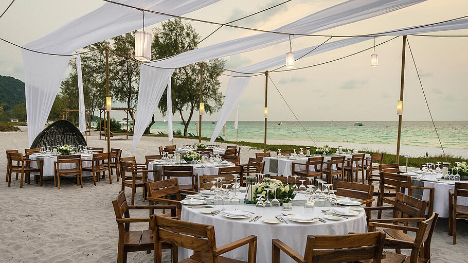 strandhochzeit       -  Hochzeit am Strand mit atemberaubender Aussicht und schlicht romantisch dekorierten Tischen.