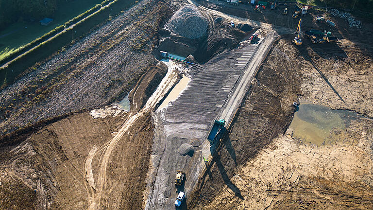 Zwischen dem Hauptdamm (links) und der neu gebauten Grundsperre wird ein neues Abflussbauwerk errichtet.