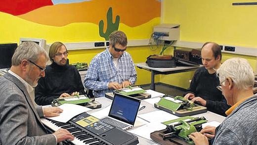 Noten tippen: Lehrer Ulrich van Aaken (links) spielt eine Melodie auf dem Keyboard vor. Die blinden Kursteilnehmer im BFW in Veitshöchheim hören genau hin und übersetzen das Gehörte auf ihren Punktschrift-Schreibmaschinen in Braille-Notenschrift.