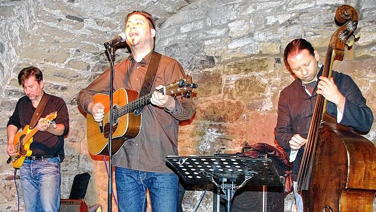 &bdquo;Americana&ldquo; ganz ohne Cowboy-Hut       -  (ay)   Zum dritten Mal war der Würzburger Musiker Dennis Schütze in der &bdquo;Kellerbühne&ldquo; des Weinhauses Zorn in Lengfurt zu Gast, diesmal mit seiner &bdquo;Acoustic Combo&ldquo;. Dazu gehörten Gitarrist Jochen Volpert und Kontrabassist Camilo Goitia. Wer Country-Musik erwartet hatte, wie im Flyer angekündigt, fand unter den knapp zwei Dutzend Songs in der Tat das eine oder andere derartige Stück. Doch: &bdquo;Nur weil ich mal einen Cowboy-Hut getragen habe bei einem Gig, ist das nicht Country, was wir hier spielen&ldquo;, sagte Gitarrist Schütze. &bdquo;Eigentlich ist das, was ich am liebsten spiele, Blues.&ldquo; Dort wo Country, Rock, Blues, Soul, Rockabilly und Rhythm & Blues zusammenkommen, spricht man von &bdquo;Americana&ldquo;. Zu den in Lengfurt gespielten Songs gehörten Eigenkompositionen von den bisher vier erschienenen Dennis-Schütze-CDs. Das Trio &bdquo;bediente&ldquo; sich aber auch bei Künstlern wie Bob Dylan, Jimi Hendrix oder Jim Croce.