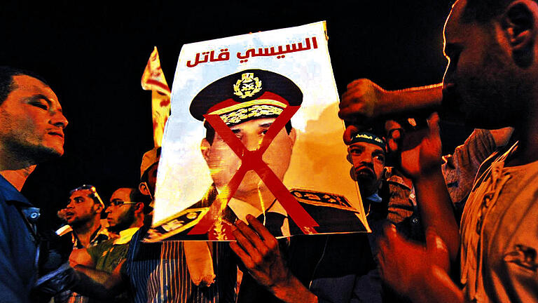 Protest gegen das Militär: Anhänger des abgesetzten ägyptischen Präsidenten Mursi verbrennen ein Foto von Armeechef El-Sissi.