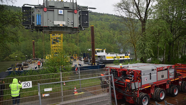 Der Trafo bewegt sich langsam auf den Schwertransporter zu, der am Ufer wartet.