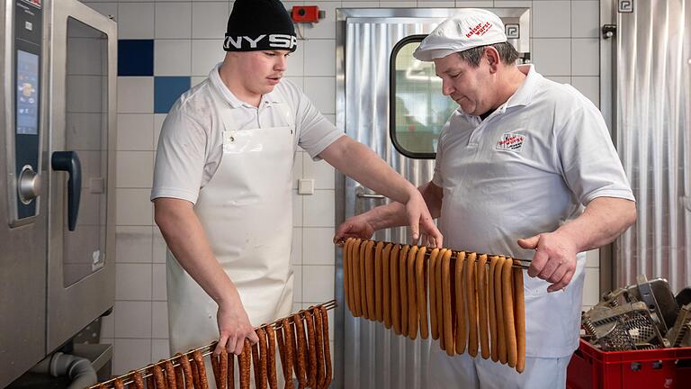 Ein Leben für die Wurst: Alfred Kaiser (rechts) leitet die Dorfmetzgerei in Aidhausen (Lkr. Haßberge) seit 25 Jahren. Sein Sohn Silas Pflüger steht als Nachfolger bereit. Die beiden sind ein Beispiel dafür, wie sich auf dem Land ein kleiner Traditionsbetrieb halten kann –auch wenn das alles andere als leicht ist. Ein Leben für die Wurst: Alfred Kaiser (rechts) leitet die Dorfmetzgerei in Aidhausen (Lkr. Haßberge) seit 25 Jahren. Sein Sohn Silas Pflüger steht als Nachfolger bereit. Die beiden sind ein Beispiel dafür, wie sich auf dem Land ein kleiner Traditionsbetrieb halten kann –auch wenn das alles andere als leicht ist.