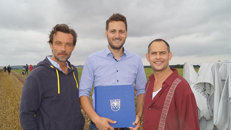 Dreharbeiten für &bdquo;Lommbock&ldquo; beginnen       -  Beim Dreh für &bdquo;Lommbock&ldquo;: Die Hauptdarsteller Lucas Gregorowicz (links) und Moritz Bleibtreu mit Kirchheims Bürgermeister Björn Jungbauer (Mitte) und dem Gästebuch der Gemeinde.