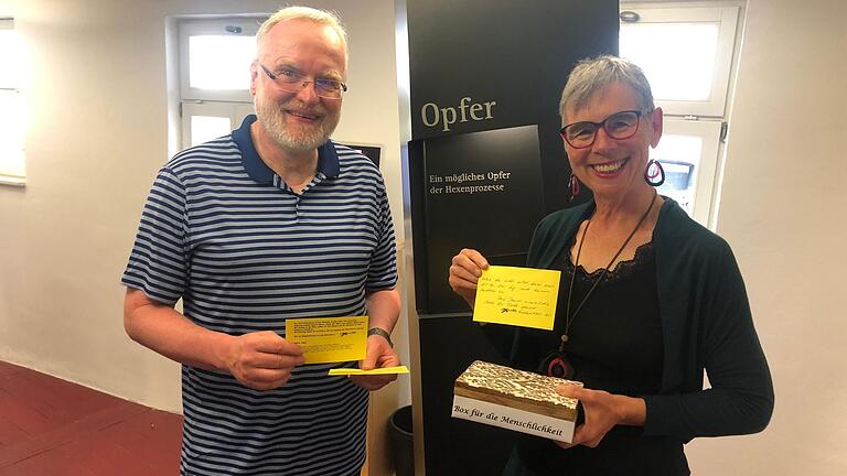Detlef Winkelmann und Monika Schraut zeigen einige Karten aus der 'Box der Menschlichkeit': Darauf können Besucherinnen und Besucher ihre Erkenntnisse aus dem Museumsbesuch festhalten.