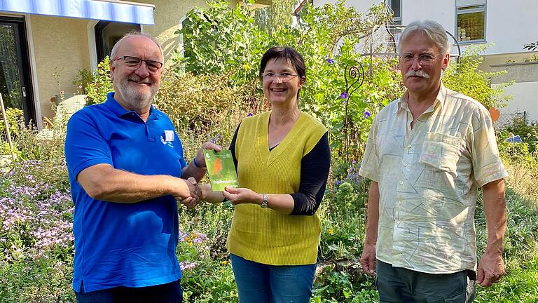 Heinrich Wilhelm vom LBV Kitzingen überreicht Michaela Fenske und Ulrich Marzolph die Auszeichnung 'Vogelfreundlicher Garten'.