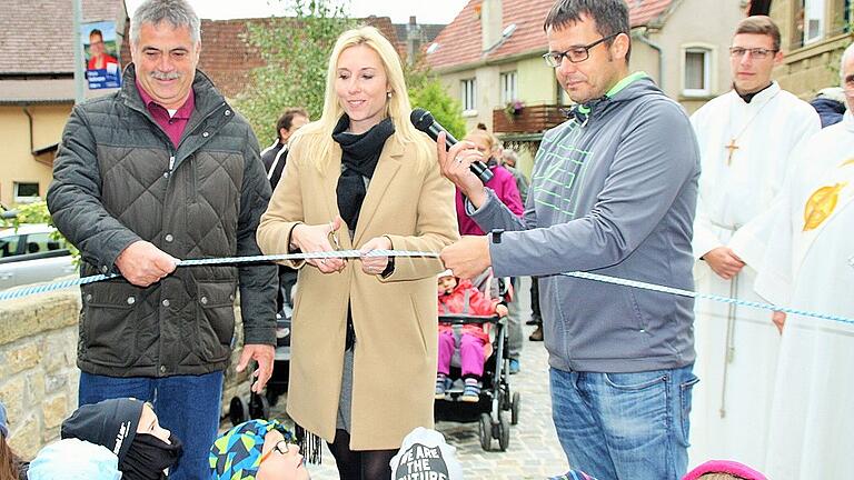 Mit dem Durchschneiden des weiß-blauen Bandes gab Bürgermeisterin Anna Stolz (Bildmitte) zusammen mit den Gänheimer Stadträten Johannes Keidel (links) und Bastian Weippert (rechts) die sanierte Bogenbrücke, die am nördlichen Ortsausgang von Gänheim die Wern und den Mühlbach überspannt, offiziell für den Verkehr frei.