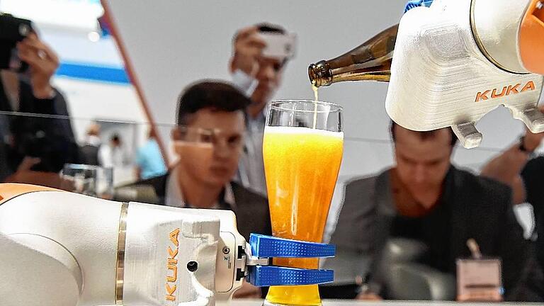 Kuka       -  Messebesucher bei der Robotik-Messe Automatica in München. Am Stand des Ausstellers Kuka schenkt ein Roboter ein Glas Weißbier ein. Tobias Hase, dpa