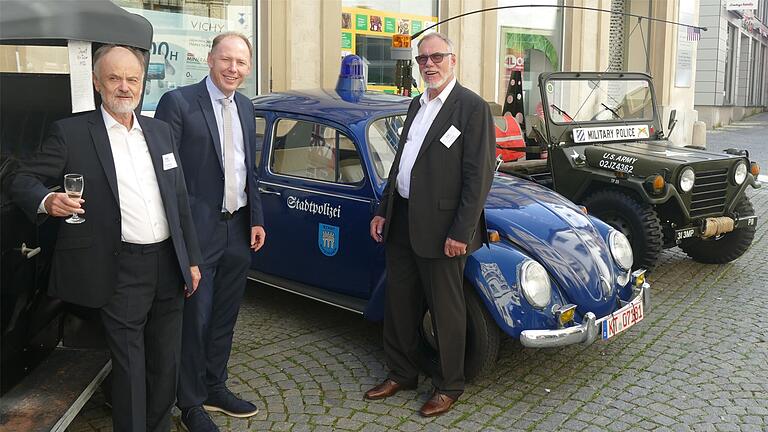 Das Bild zeigt (von links ) Rainer Gutzeit, OB Stefan Güntner und AMC-Chef Claus Bader vor zwei Polizeifahrzeugen, die einst das Stadtbild prägten: der legendäre Kitzinger Stadtpolizei-Käfer und ein in Privatbesitz gehaltener Jeep der US-Military Police.