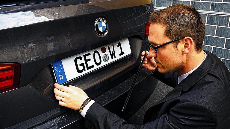 GEO-Bürgermeister fährt jetzt voll auf GEO ab: Thorsten Wozniak clippt sein GEO-Nummernschild &bdquo;GEO &ndash; W 1&ldquo; auf seinem Auto fest.