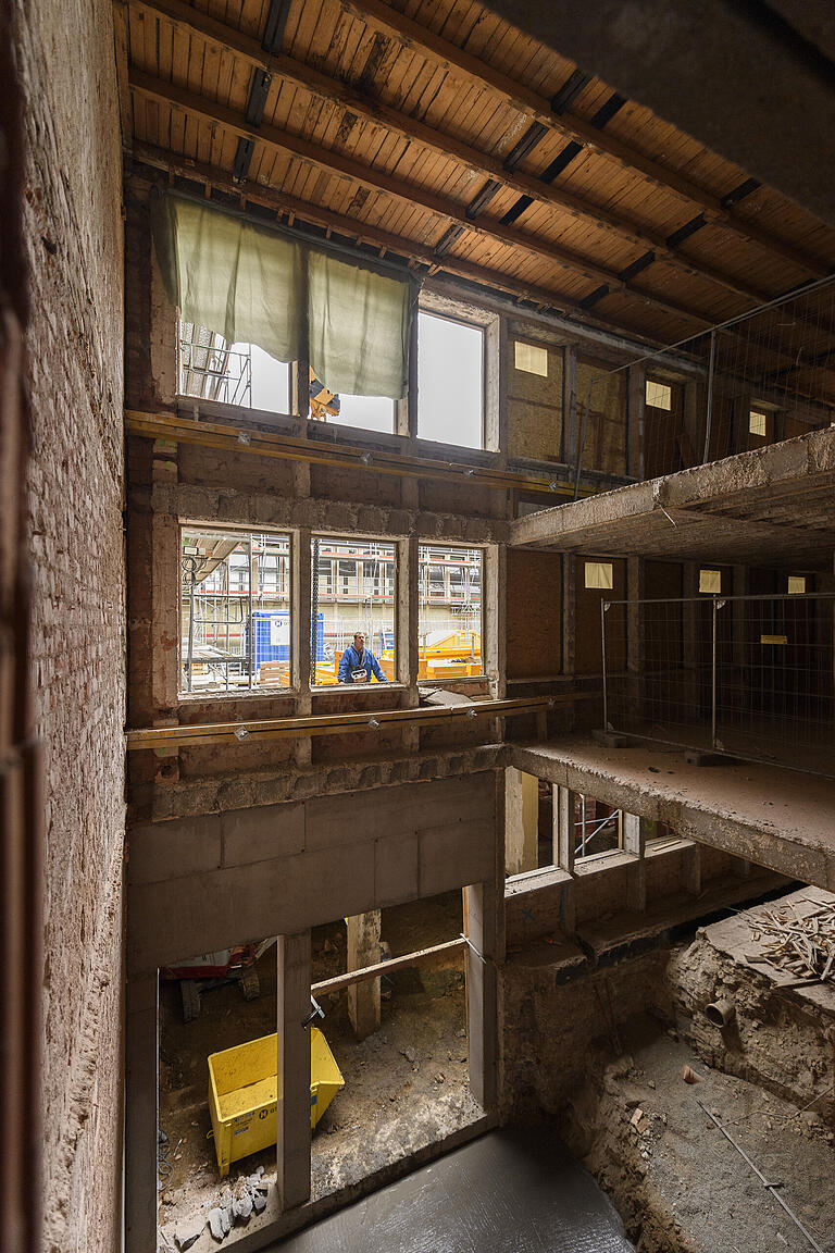 Blick vom Untergeschoss bis zum Dach. Vor der ehemaligen Gymnastikhalle wird der Aufzugsschacht gebaut. Der Boden ist frisch betoniert.