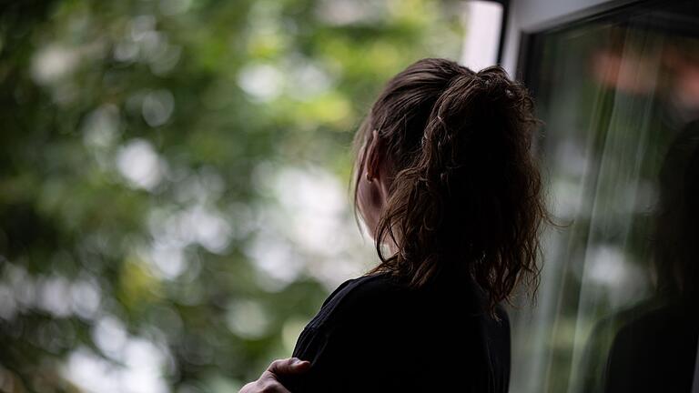 Eine Frau steht am Fenster       -  Einsamkeit betrifft zunehmend auch jüngere Erwachsene und Menschen, die nicht allein leben, wie eine aktuelle Studie zeigt.