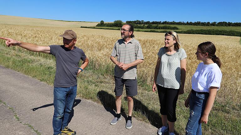 Oliver Giel zeigt, wie nahe das Gewerbegebiet 'Schlettach II' an das gleichnamige Wäldchen im Nordosten von Haßfurt heranrücken wird. Oliver Giel möchte zusammen mit Klaus Roßdeutsch, Yvonne Wurl und Gina Roßdeutsch (von links) den Stadtrat davon überzeugen, sich gegen dieses Gewerbegebiet auszusprechen. Im Hintergrund die gebüschbewachsene Böschung, für die die Umweltschützer starke Beeinträchtigungen durch eine 18 Meter hohe Halle befürchten.