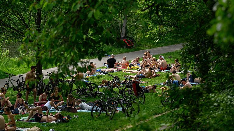 Dicht an dicht liegen junge Menschen im Sommer 2022 am Mainufer in der Sanderau in Würzburg.