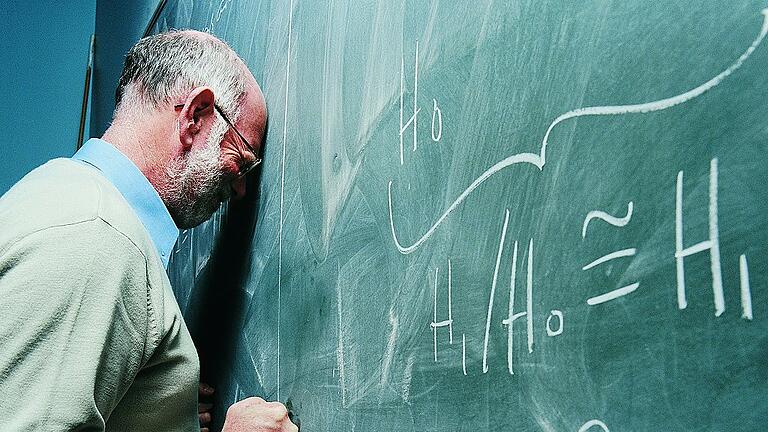 Portrait of a Frustrated Maths Lecturer Banging his Head Against a Blackboard       -  Viele Lehrer schweigen, wenn sie Opfer von Gewalt oder Mobbing werden. Symbolfoto: Getty Images