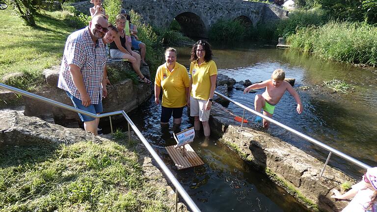 Nicole Endres und Natascha Link, 1. und 2. Vorsitzende des Musikvereins Stockheim, ließen das kleine Saale-Musicum-Floß am Tretbecken in Stockheim zu Wasser, beäugt von Bürgermeister Martin Link (links) und Kuno Holzheimer, Projektleitung der Bayerischen Musikakademie Hammelburg.