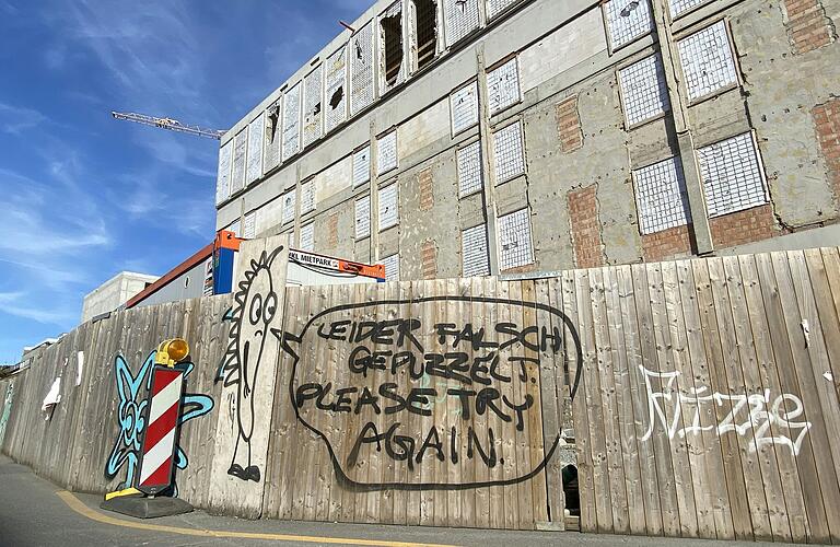 'Please try again' steht auf einem Graffito am Bauzaun des Mainfranken Theaters in der Ludwigstraße in Würzburg: Ganz von vorn angefangen werden muss zwar nicht, aber nach dem Ausfall des ersten Planungsbüros muss nun auch noch eine neue Fachplanung für die Haustechnik gefunden werden.