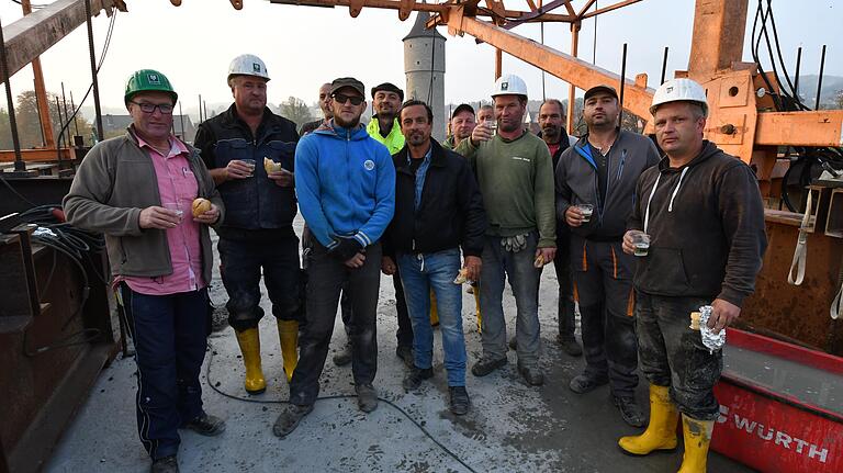 Mit belegten Brötchen und Sekt aus dem Plastikbecher stößt Polier Raimund Eckardt (links) mit seinen Kollegen auf die Vollendung des Brückenrohbaus an.