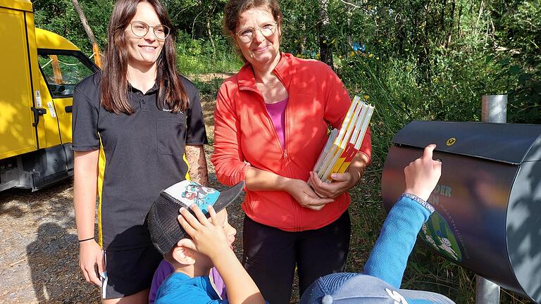 Laura Brindöpke von der Deutschen Post (links) brachte den Kindern des Waldkindergartens 'Grüne Wichtel' und Beatrice Gottier, Leiterin des Waldkindergartens, im Namen ihrer Kolleginnen und Kollegen einen neuen Briefkasten und einen Stapel Sachbücher über die Post.