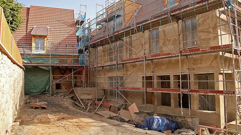 Trotz mancher Hindernisse nimmt der Bau des Bürgerhofs in Erlabrunn Formen an. Die den Innenhof umgebende Natursteinmauer (links) ist saniert, am Gebäude ist der Grundputz aufgetragen. Bei einem Ortstermin entschied der Gemeinderat nun über die Anordnung und Größe von Pflanzbeeten entlang der umlaufenden Natursteinmauer sowie den Boden in der Kulturscheune (im Bild hinten).