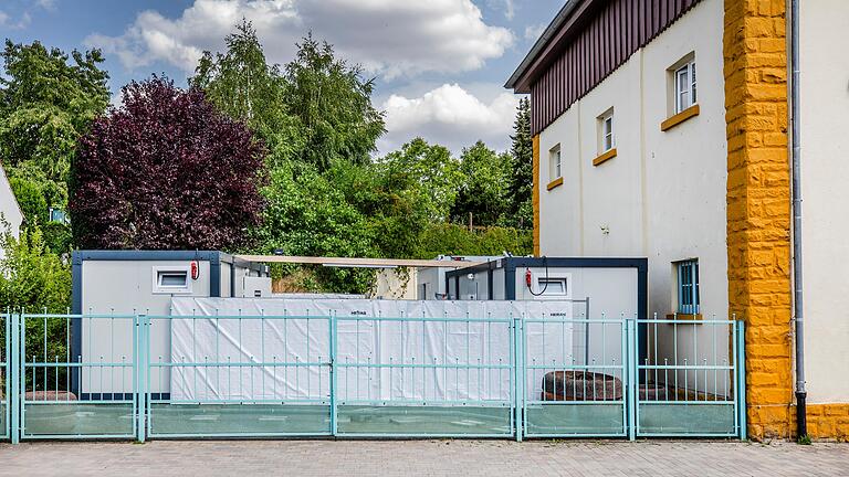 Neben dem Gebäude der Notunterkunft Unterpleichfeld stehen Container im Innenhof, die von außen verdeckt sind. Als bekannt wurde, dass aus dem ehemaligen Antikhaus eine Notunterkunft wird, trug der Gemeinderat 'Ängste aus der Bevölkerung' an den Bürgermeister heran.