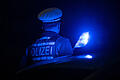 Illustration - Polizei       -  Ein Polizist steht neben einem Polizeifahrzeug (Symbolbild)