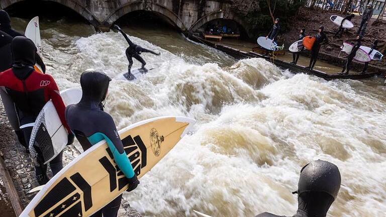 Die Eisbachwelle am Rand des Englischen Gartens in München ist gut besucht. Der Freizeit-Hotspot ist das ganze Jahr über ein Magnet für Wellenreiter. Foto: Peter Kneffel/dpa       -  Die Eisbachwelle am Rand des Englischen Gartens in München ist gut besucht. Der Freizeit-Hotspot ist das ganze Jahr über ein Magnet für Wellenreiter.