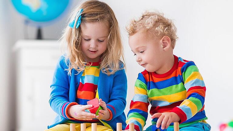 Kids playing with wooden toy train       -  Womit spielst Du gern? Manchmal reichen schon Bauklötzchen, mit denen sich Kinder stundenlang beschäftigen können.