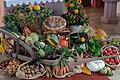 Obst und Gemüse aus heimischen Gärten, arrangiert auf einer alten Holzschubkarre und Strohballen, schmücken den Erntedank-Altar.