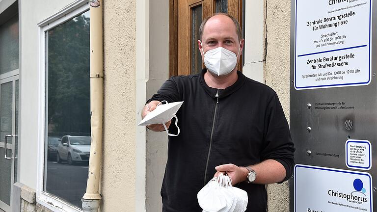 Michael Thiergärtner überreicht einem neu ankommenden Gast der Kurzzeitübernachtung eine Maske.