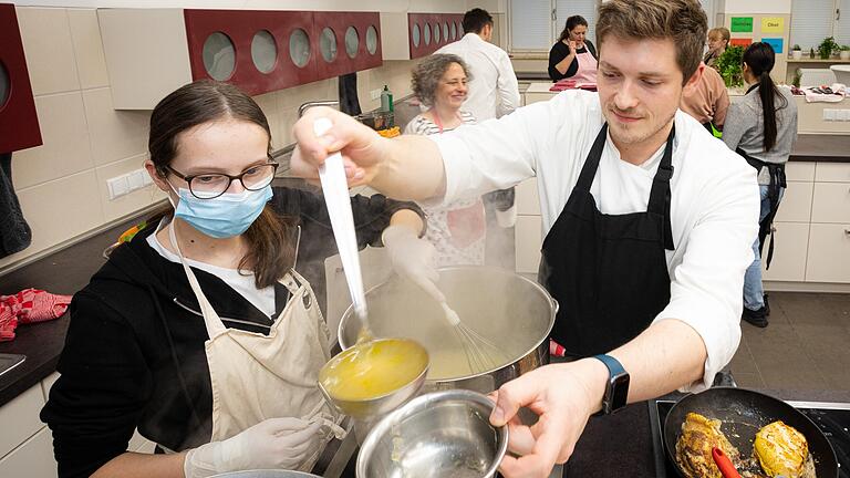 Dennis Imhof von Hotel und Restaurant Imhof in Gemünden bereitet mit einer Schülerin der St. Ursula Schule eine Brühe vor.