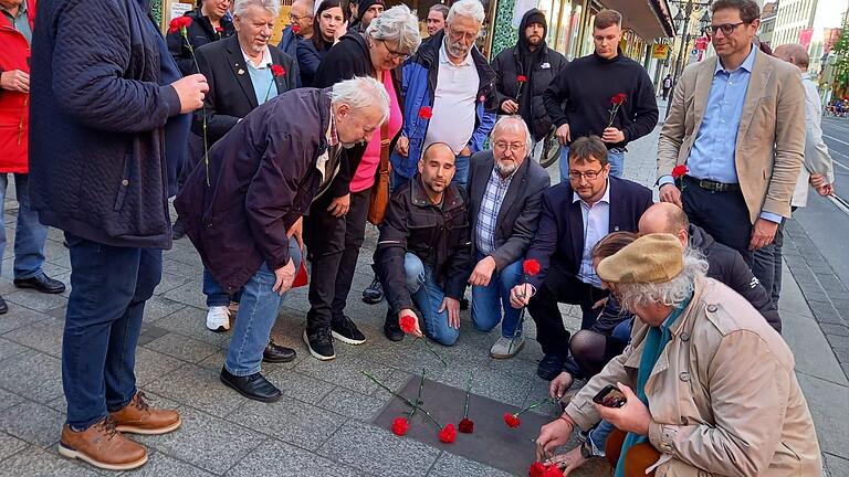 Teilnehmer aus den Gewerkschaften und aus der Lokalpolitik legen rote Nelken am Gedenkstein nieder.