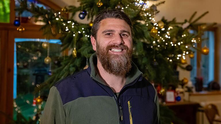 Hausvater Peter Fleischhauer vor dem festliche geschmückten Weihnachtsbaum in der Wiesenmühle.