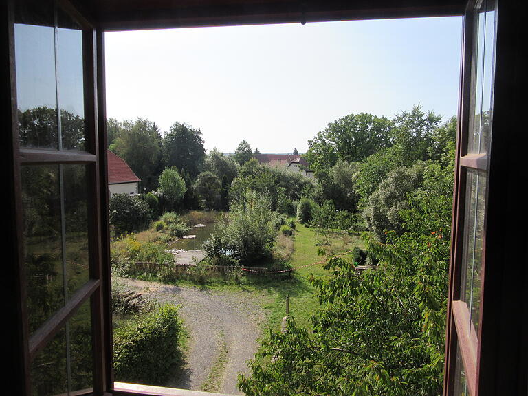 Beim Blick aus der Propstei breitet sich der Garten mit dem Schwimmteich vor dem Blick des Betrachters aus.