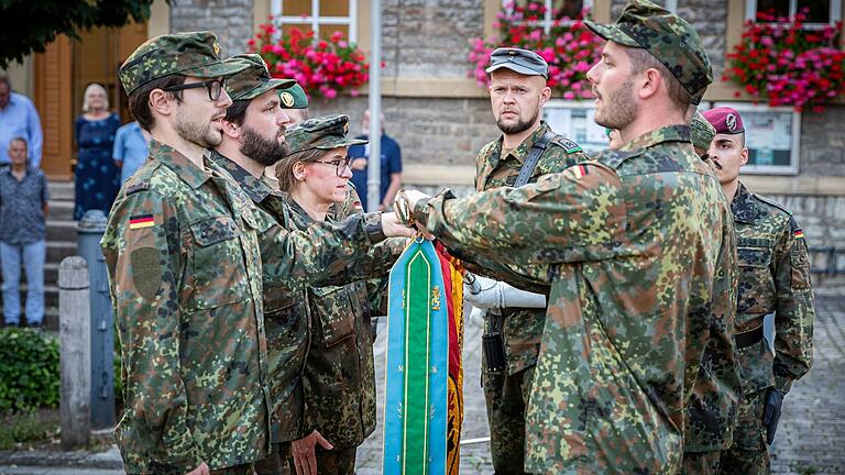 Sechs Teilnehmergeloben mit der Hand auf der Truppenfahne der Infanterieschule.&nbsp;