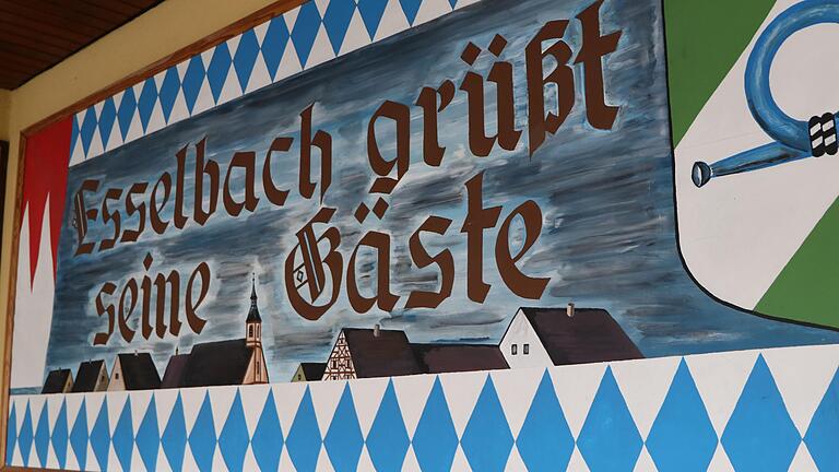 &quot;Esselbach grüßt seine Gäste&quot; steht auf einem Schild im Eingangsbereich der Esselbacher Festhalle.