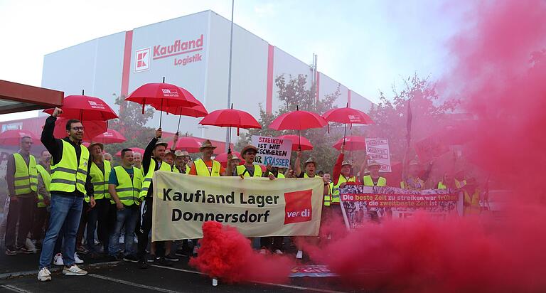 Mit roten Schirmen, mächtig Frust und reichlich Rauch verdeutlichten die Beschäftigten ihr Missfallen über das derzeitige Tarifangebot der Arbeitgeber bei einer Streikkundgebung am Kaufland Lager in Donnersdorf.