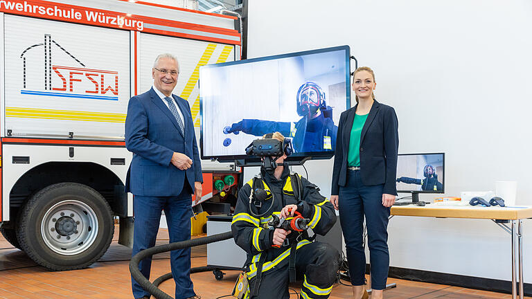 Bayerns FFW-Leute können künftig die Brandbekämpfung im Innenbereich mit einer neuen virtuellen Trainingsanlage realitätsnah und völlig gefahrlos üben. Zu Besuch waren Joachim Herrmann (links, Bayerischer Staatsminister des Innern) und Judith Gerlach(rechts, Staatsministerin für Digitales von Bayern). Ein Feuerwehrmann führt die VR-Übung vor.