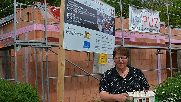 Johanna Dietz, Leiterin der ambulanten Altenhilfe im Kreiscaritasverband Rhön-Grabfeld mit dem aus Legosteinen gebauten Pflegeübungszentrum im Kleinformat. Hinter ihr stehen schon die Mauern der künftigen Einrichtung